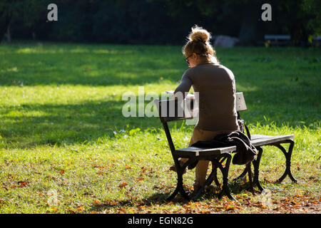 Attraente ragazza leggendo un libro in un caldo pomeriggio di sole nel parco Lazienkowski, Varsavia Foto Stock