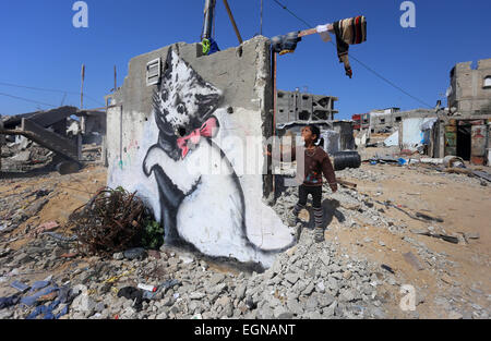 (150227) -- GAZA, 27 febbraio 2015 (Xinhua) -- una ragazza palestinese sorge accanto a un murale di un gattino che è stato dipinto da British artista di strada Banksy sui resti di un tempio che fu distrutto durante la 50-giorno offensiva israeliana sulla Striscia di Gaza negli ultimi mesi di luglio e agosto, nel nord della Striscia di Gaza città di Beit Hanun nel febbraio 27, 2015 (Xinhua/Yasser Qudih) Foto Stock