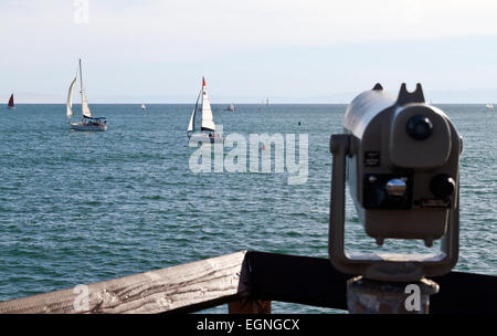 Un telescopio su un molo si affaccia su barche a vela. Foto Stock