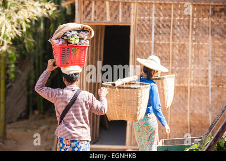 Donne locali che effettuano il trasporto di merci da parte della testa di caricamento, e cesti tramite un palo di bambù al mercato ortofrutticolo,Lago Inle, Shan,Birmania,Myanmar, Foto Stock