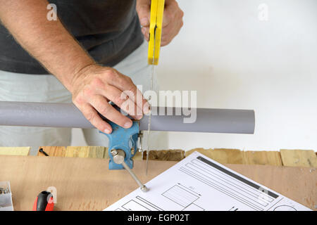 Un idraulico tagliare il tubo in PVC con SAW Foto Stock