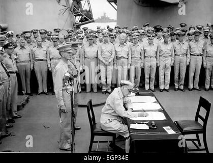 Resa giapponese General Douglas MacArthur segni come Allied Comandante supremo Giapponese durante le cerimonie di consegna sulla USS Missouri nella Baia di Tokyo, 2 settembre 1945. Dietro di lui ci sono General Jonathan Wainwright e generale britannico Arthur Percival. Foto Stock