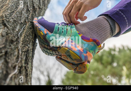 La donna occupare lacci delle scarpe pendente con la calzatura su albero Foto Stock