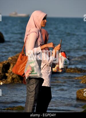 Hua Hin, Thailandia: due donne Musulmane di indossare le sciarpe di testa e portante 7-11 borse per lo shopping sulla spiaggia Foto Stock