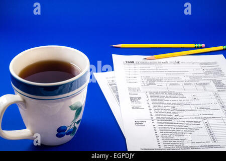 Rilassante tazza di caffè nero in una tazza in gres con matite e IRS 1040 forma fiscale su sfondo blu Foto Stock