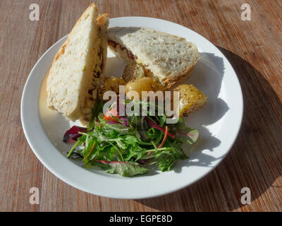 Pranzo snack di formaggio Cheddar e data chutney sandwich nel granaio pane con insalata mista e patate sesamo in una caffetteria Foto Stock