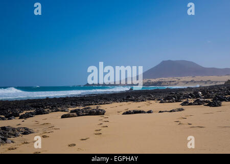 Sabbia dorata sotto un cielo blu con fosco scenario di montagna sulla spiaggia Corralejo Fuerteventura [Las Palmas] [isole canarie Spagna]. Foto Stock