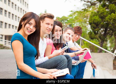 Felice giovane gruppo di studenti seduti sul gradino Foto Stock