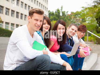 Felice giovane gruppo di studenti seduti sul gradino Foto Stock