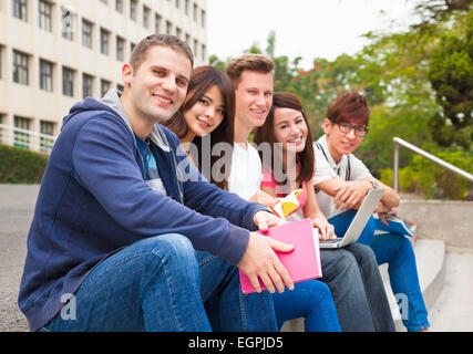 Felice giovane gruppo di studenti seduti sul gradino Foto Stock