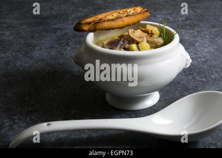 Zuppa di verdure nella ciotola in bianco su sfondo scuro con texture Foto Stock