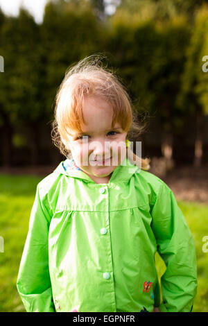 Ritratto di una giovane ragazza in un parco con un cappotto di pioggia. Questo lifetsyle foto è stata ripresa con luce naturale. Foto Stock