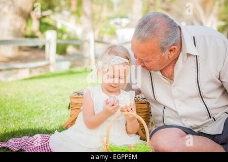 Amare il nonno e la nipote godendo le uova di Pasqua su una Coperta picnic al parco. Foto Stock