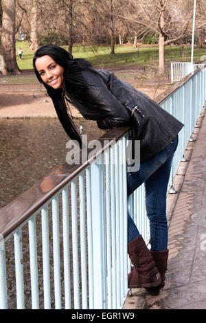 Un attraente giovane donna appoggiata su un ponte di St James Park London e sorridente Foto Stock