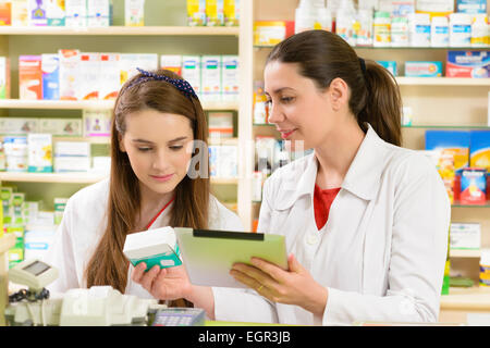 Due giovani donne farmacista in una farmacia lavorando su un tablet pc Foto Stock