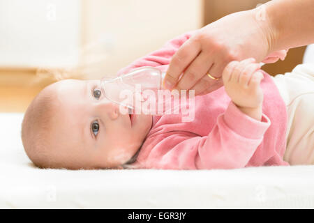 Baby tenendo la terapia respiratoria. mano che tiene la maschera di un nebulizzatore. Foto Stock