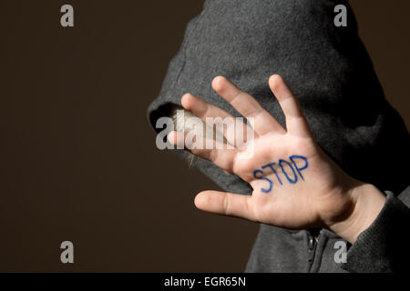 Sconvolto abusato spaventati bambino (boy), fermare la mano jesture close up orizzontali scure ritratto con spazio di copia Foto Stock