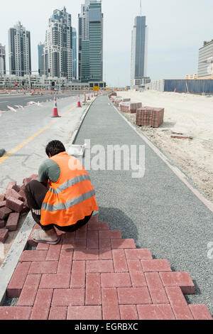 Lavoratore la posa di pavimentazioni di blocco sul sentiero in Dubai Emirati Arabi Uniti Foto Stock