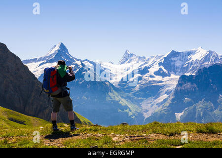 Walker fotografando le aspre montagne delle Alpi Bernesi, elevata al di sopra di Grindelwald, Svizzera Foto Stock