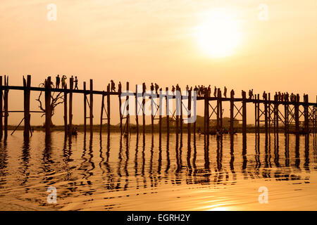 Le persone che attraversano la U Bein ponte sopra il lago Taungthaman al tramonto, Mandalay Myanmar ( Birmania ), Asia Foto Stock