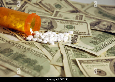 La prescrizione di una bottiglia di vino bianco pillole spargimento su una pila di $100 fatture del dollaro Foto Stock