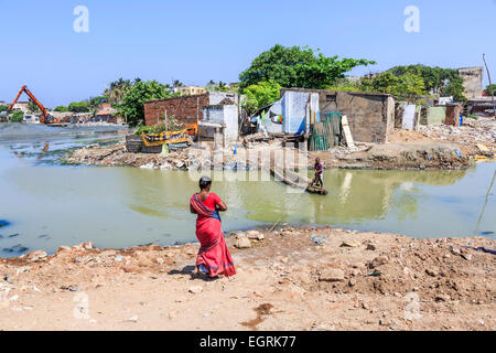 Donna locale in sari colorati in attesa di realizzare localmente un traghetto in legno azionato da un ragazzo in una delle baraccopoli di Chennai, nello Stato del Tamil Nadu Foto Stock