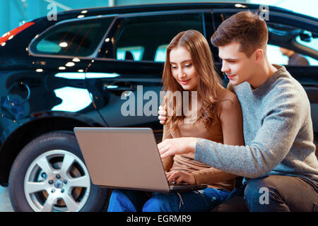 Felice coppia giovane in concessionaria Foto Stock