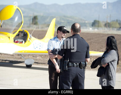 Irvine, California, USA. Xvii gen, 2015. Il pilota di un Evektor stella di sport del motore unico sotto l'ala biposto aereo fuori dall'Aeroporto John Wayne, insieme con la sua femmina passeggero, parla con un Irvine sergente di polizia dopo aver effettuato un atterraggio di emergenza presso il grande parco di sabato mattina.--------Un Evektor stella di sport del motore unico sotto l'ala biposto aereo fuori dall'Aeroporto John Wayne fecero un atterraggio di emergenza sabato mattina al grande parco a Irvine. Il piano maschio del pilota è stato accompagnato da una femmina sbarcati passeggeri in modo sicuro senza lesioni o danni visibili al piano. Irvine Foto Stock