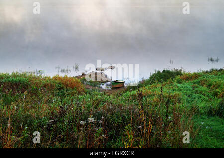 Foggy sunrize fiume. La barca sulla riva del fiume. Foto Stock