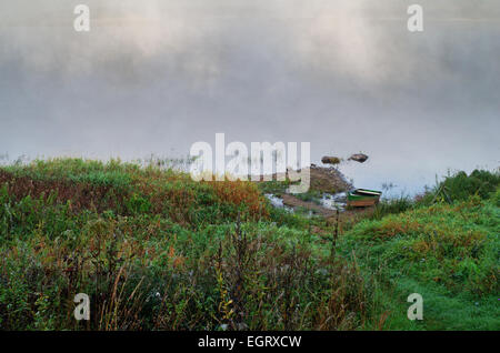 Foggy sunrize fiume. La barca sulla riva del fiume. Foto Stock