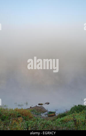 Foggy sunrize fiume. La barca sulla riva del fiume. Foto Stock