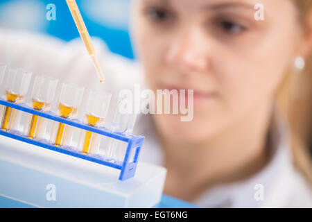 Le giovani donne di scienza di pipettaggio professionale la soluzione nella provetta di vetro. Foto Stock