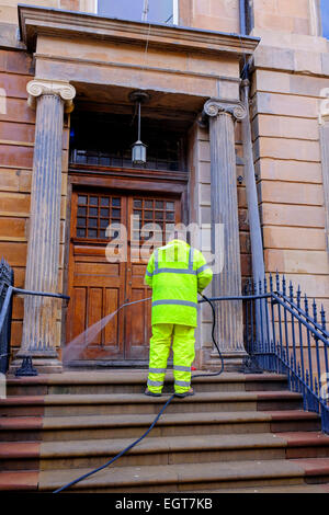 Workman utilizzando una idropulitrice ad alta pressione per il clan il fiore di pietra arenaria colorata facciata di un edificio, Bath Street, Glasgow, Scozia Foto Stock