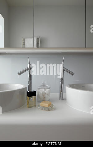 Dettaglio simmetrica di doppi lavabi con cromo rubinetti miscelatori montato su Corian vanità sotto unità mirrored cabinet nel Regno Unito mostrano home Foto Stock