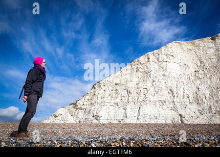 Su un soleggiato inverno freddo giorno con uno sfondo di cielo blu, una donna si ammira la prima delle sette sorelle chalk cliffs. Foto Stock