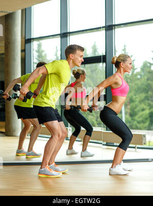Uomo sorridente e la donna con manubri in palestra Foto Stock