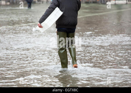 Close Up di gambe con scarponi dovuta all'acqua alta. Questo flusso si verifica quando vi è alta marea a Venezia, Italia. Foto Stock