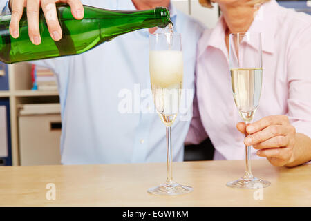 Vecchia coppia versando champagne in vetro per Capodanno Foto Stock