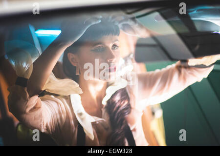 Donna che fissa i suoi capelli in auto. Foto Stock