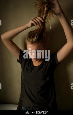 Teen girl che fissa i suoi capelli. Foto Stock