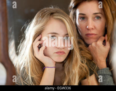 Madre e figlia teenager il loro appoggio i menti in mani. Foto Stock