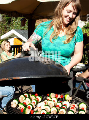 Donna coperchio di sollevamento sul grill. Foto Stock
