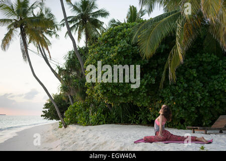 Donna fare yoga sulla spiaggia alle Maldive. Foto Stock