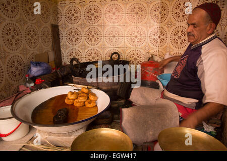 L'uomo vendere le ciambelle (Sfenj) nel souk marocchino, Marrakech. Foto Stock