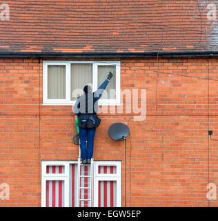 Un uomo su una scala la pulizia di vetri England Regno Unito Foto Stock