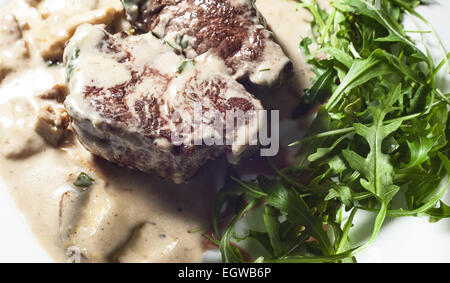 Bistecca con crema e funghi, servita su piastra bianca. Foto Stock