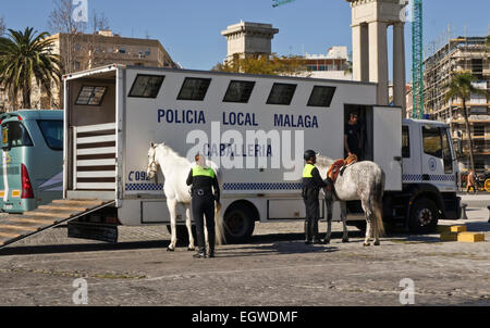 Lo spagnolo gli ufficiali di polizia la preparazione di cavalli prima di pattugliamento city, Malaga, Spagna. Foto Stock