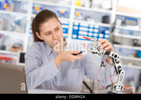 Schoolgirl regola il braccio di robot modello, ragazza in un laboratorio di robotica Foto Stock