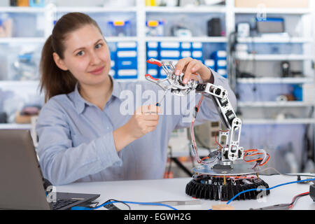 Schoolgirl regola il braccio di robot modello, ragazza in un laboratorio di robotica Foto Stock