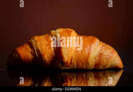 Croissant fresco isolato su una superficie a specchio Foto Stock